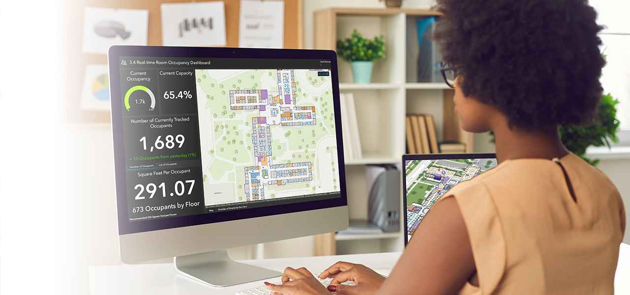 Donna che lavora a un computer che visualizza i dati indoor con un dashboard con numeri e guarda le mappe indoor