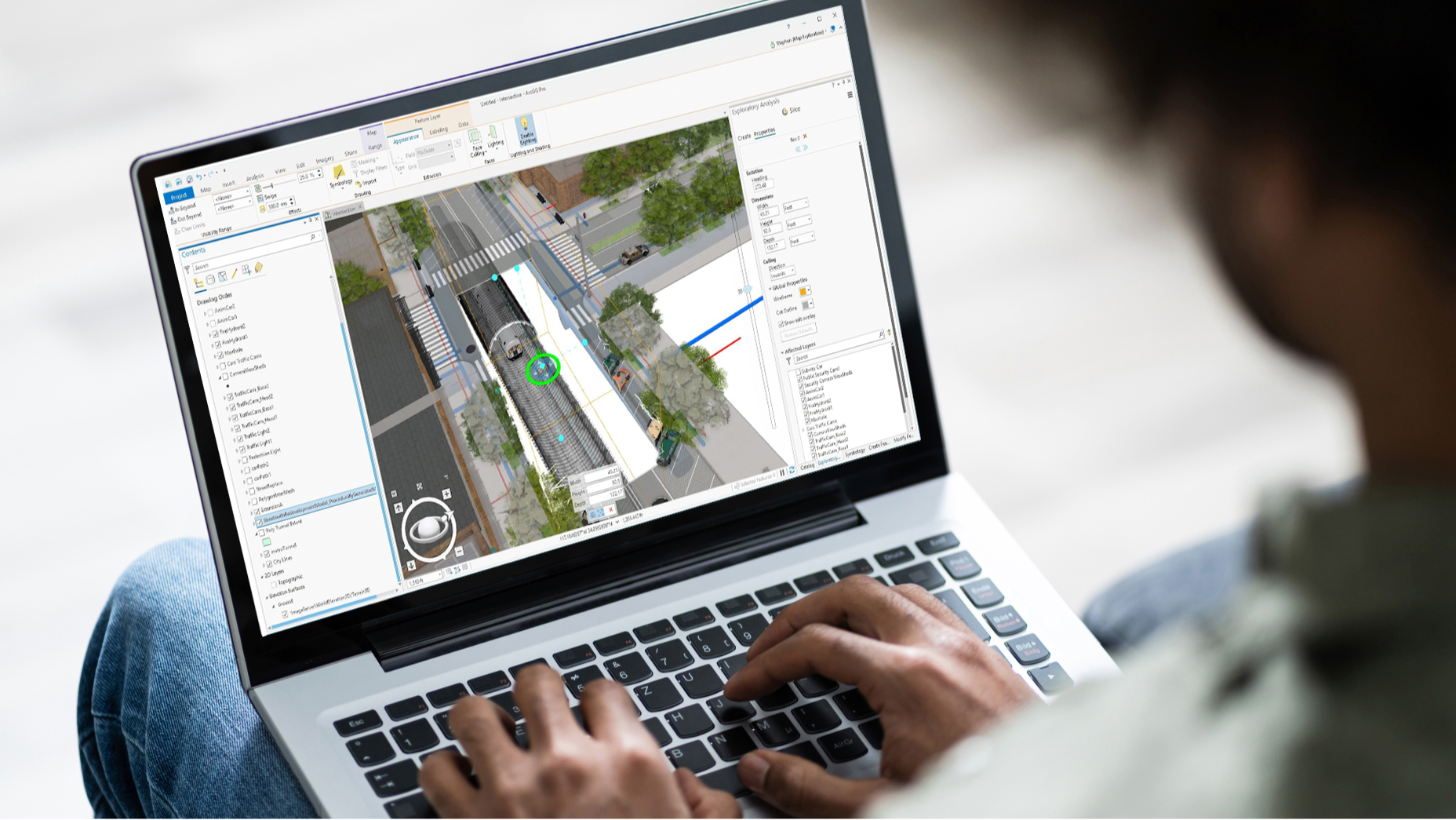 Una persona su un laptop che mostra una scena 3D di edifici, vegetazione e testo