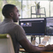 A person sitting at a desk using a computer with two monitors displaying modeling software