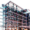 A black-and-white 3D model of a city block with two taller buildings highlighted in pale orange