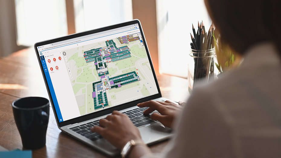 Una persona che lavora da casa su un laptop usando ArcGIS Indoors per verificare l'uso dello spazio in una mappa di interni