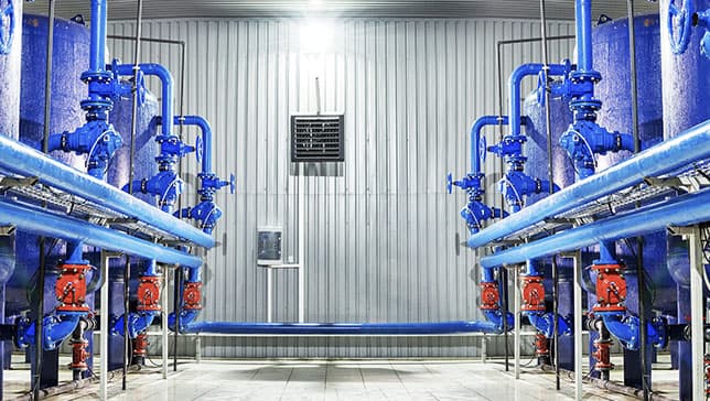 Una stanza luminosa, con pareti di metalli corrugato contenente serbatoi e condotte blu
