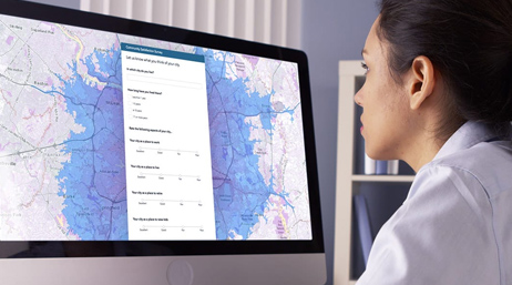 Woman viewing a large map on a computer monitor