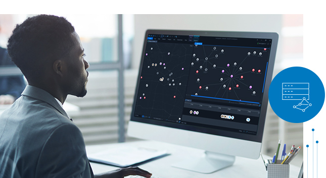 Giovane uomo che lavora al computer con un monitor grande su cui sono mostrati dei dati simbolizzati su una mappa e nel grafico dei collegamenti