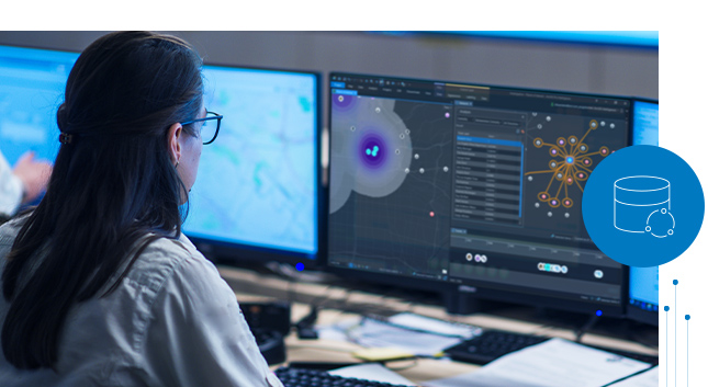 Giovane donna davanti a un monitor che guarda dati visualizzati tramite strati di mappatura con un diagramma di analisi dei collegamenti e una tabella