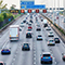 A wide, busy highway filled with cars under a bright sunny sky