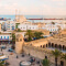 An old city with historic buildings with the ocean stretching on behind them 