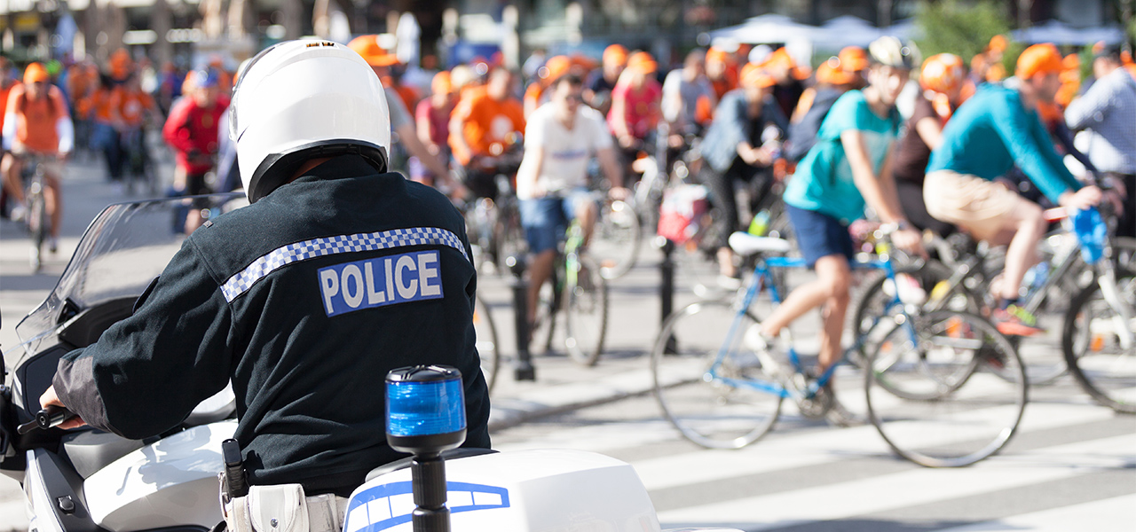 Agente di polizia su una motocicletta vicino a un gruppo di persone in bici