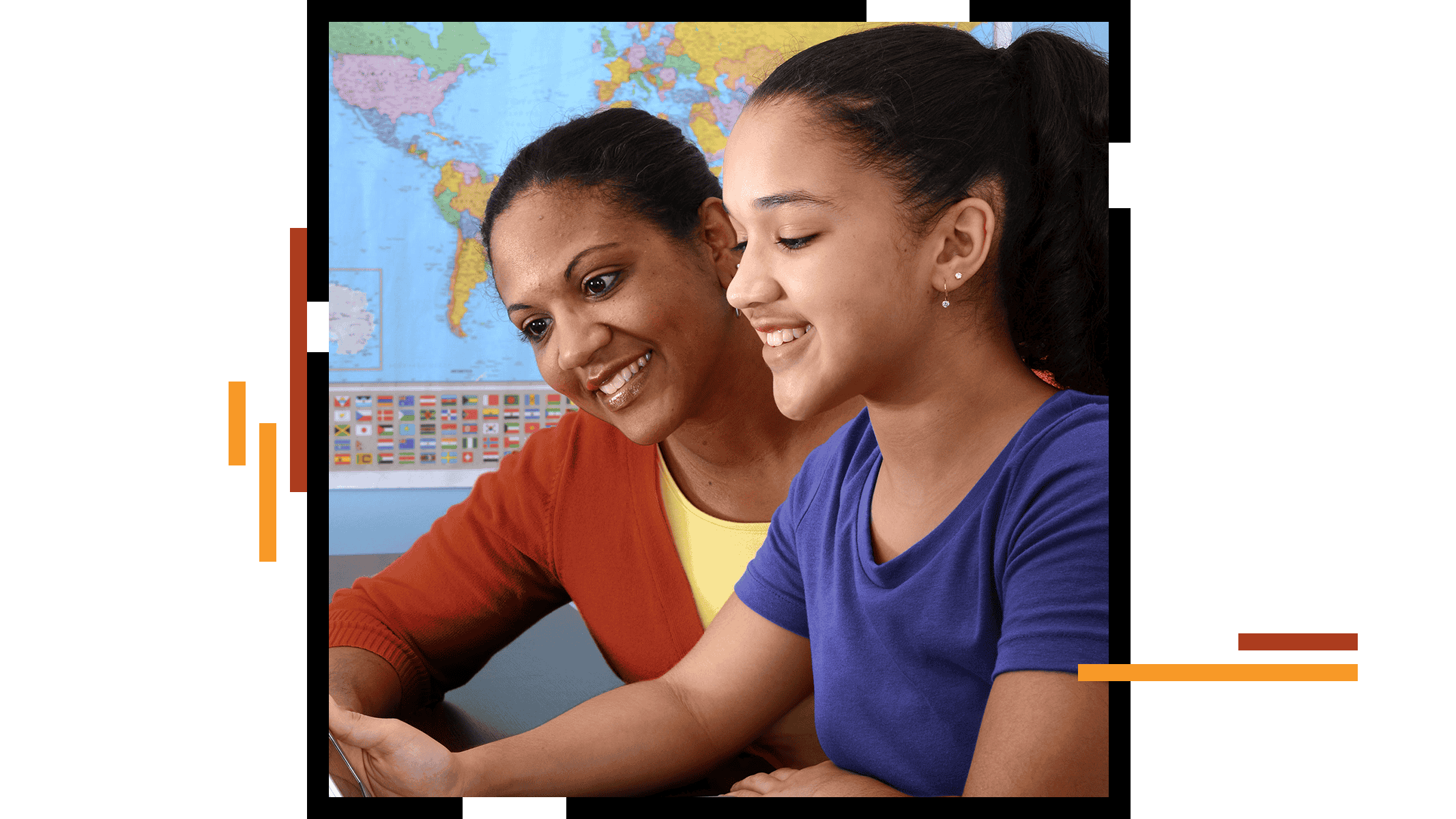 Un insegnante seduto accanto a uno studente sorridente mentre discutono del display di un computer in una classe con una mappa del mondo sullo sfondo