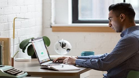 Uomo seduto a una scrivania che scrive sul suo portatile e lancia un modello di ArcGIS Hub