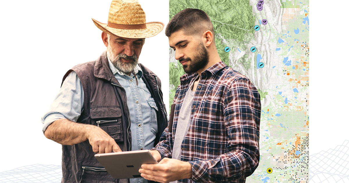 Two people dressed for outdoor research discussing a shared tablet screen with a contour map in the background