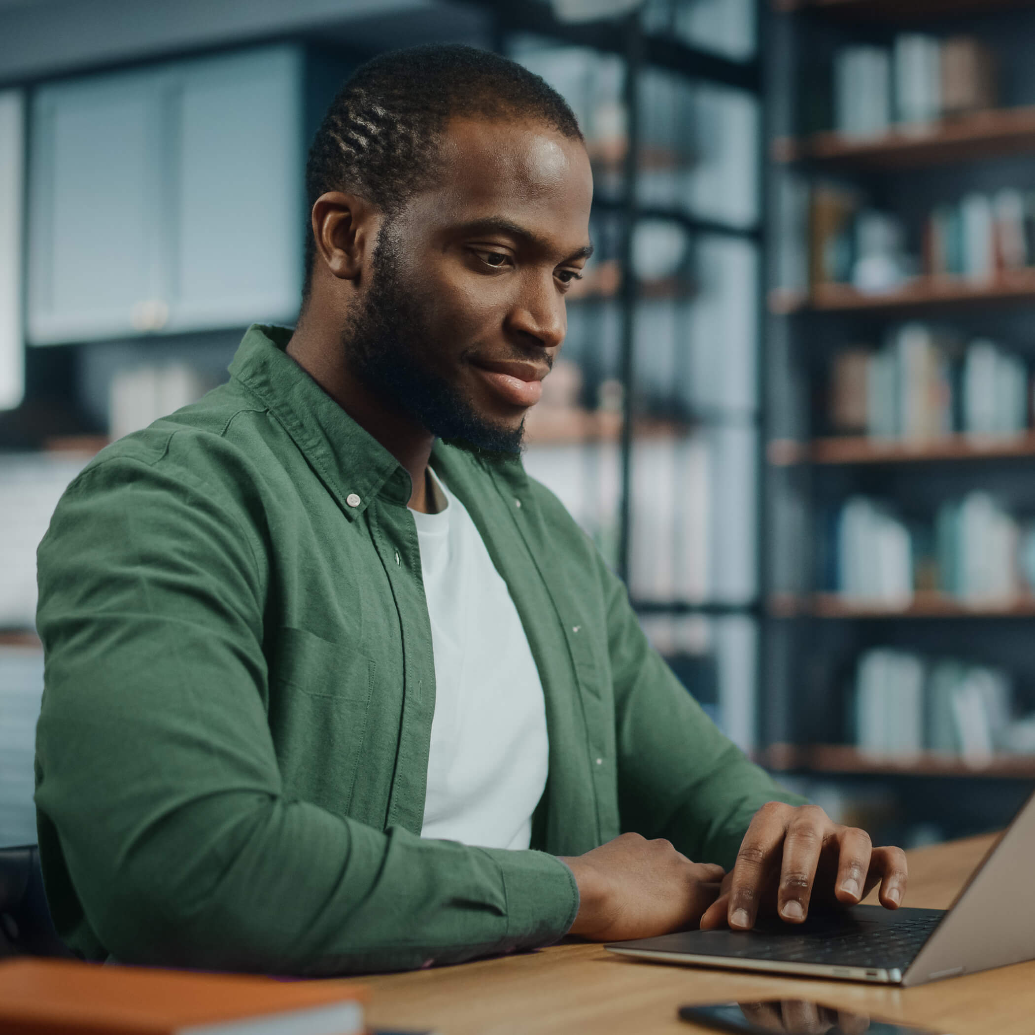 A person sitting at a desk typing at his laptop