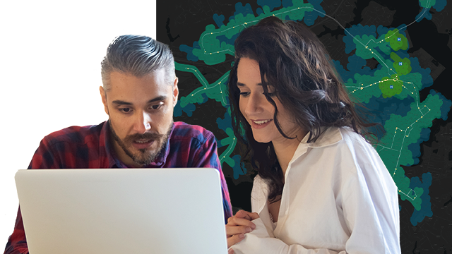 Two people sitting at a desk looking at a laptop, and a map background
