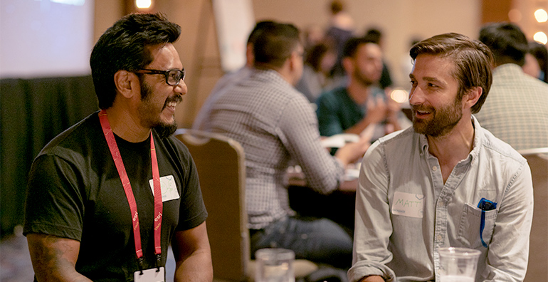 Two conference attendees sitting in a user testing area talking at a table