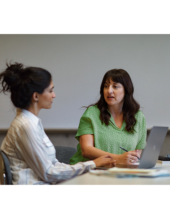 A businessperson typing on a computer at an office desk, and a group of colleagues chatting in a lobby seating area