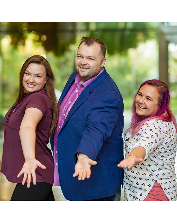 Three Esri employees posing for the camera with their left hands extended out, and a group of three people sitting together talking about papers in front of them